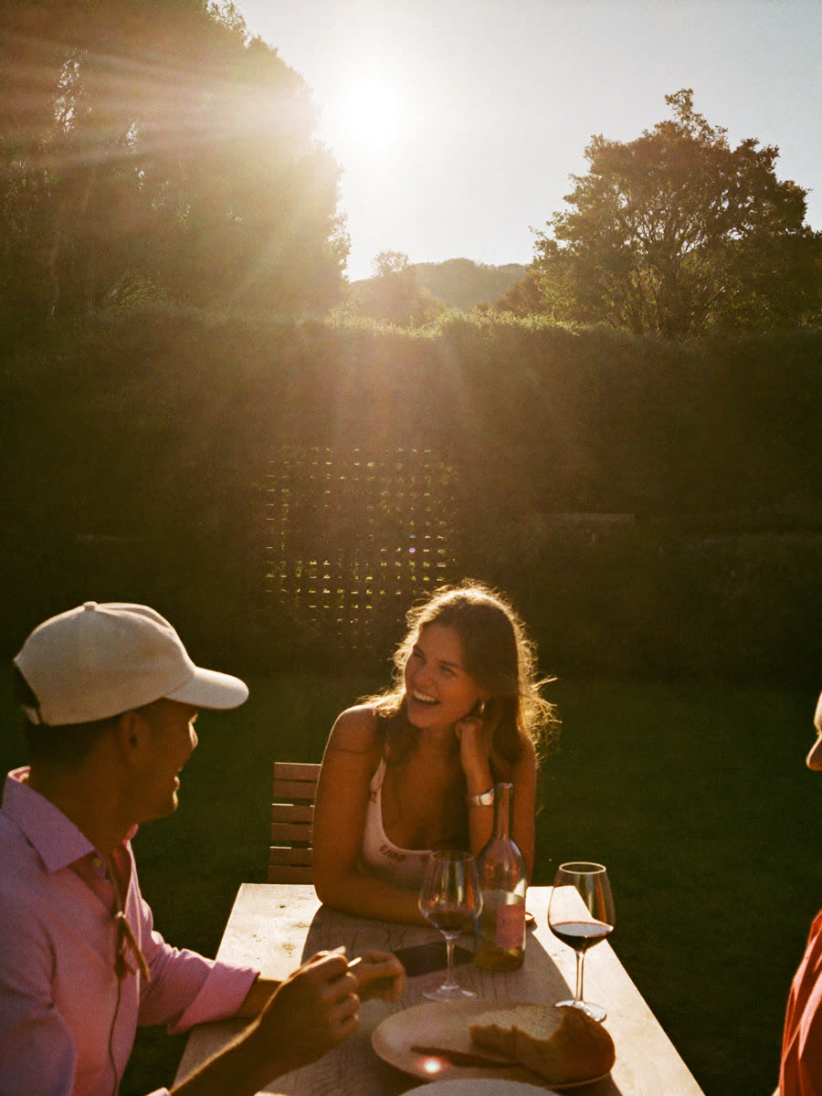 Friends laughing around an outdoor table, no phones in sight