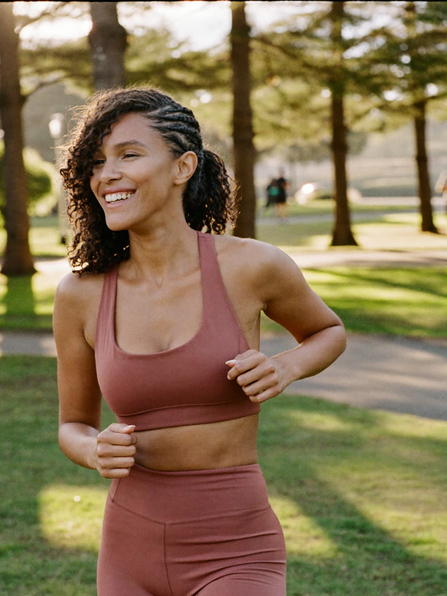 A woman in workout clothes jogging through a sunny park