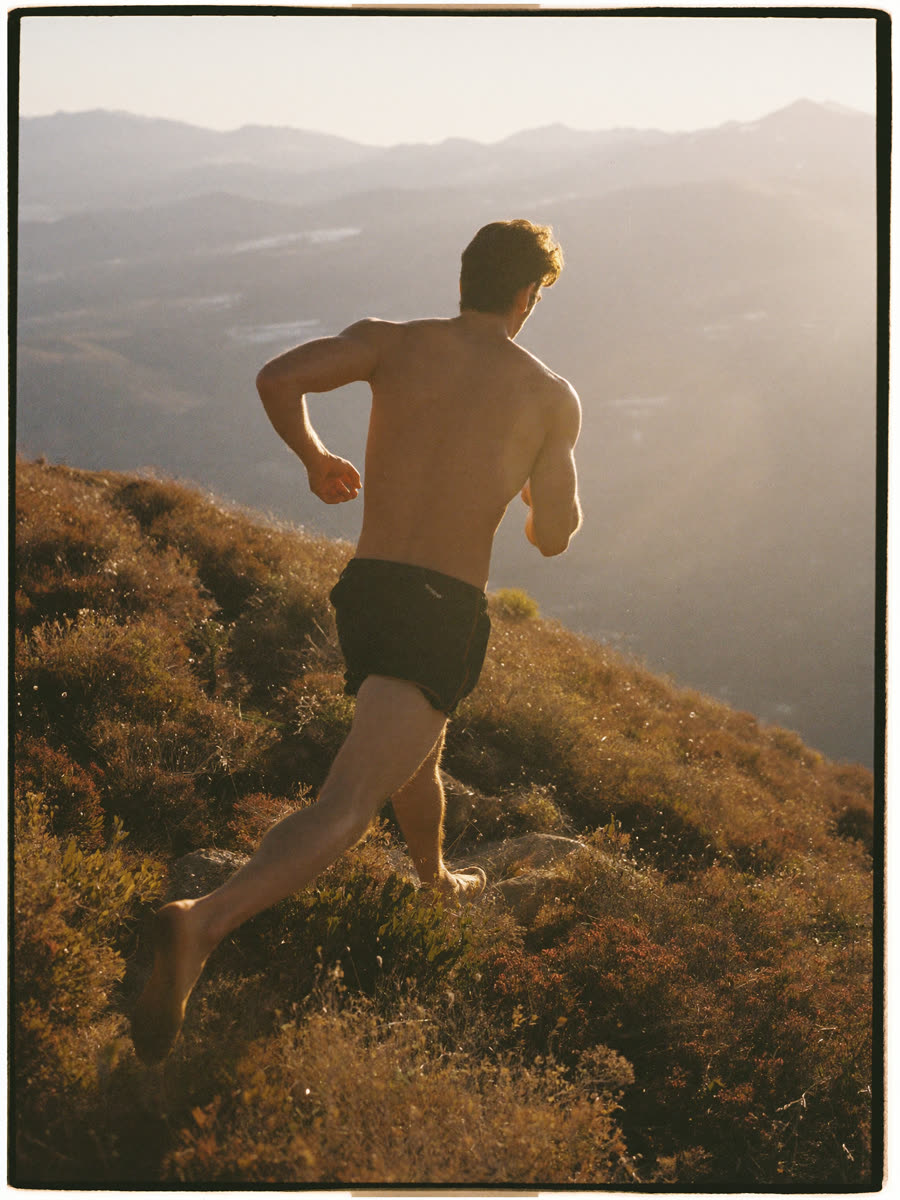 A man trail-running along a mountain ridge at golden hour